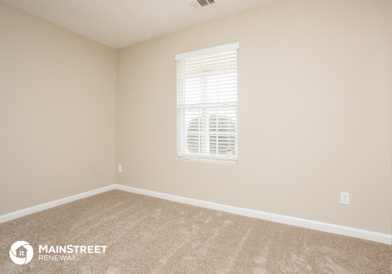 the upstairs bedroom with carpet and a window