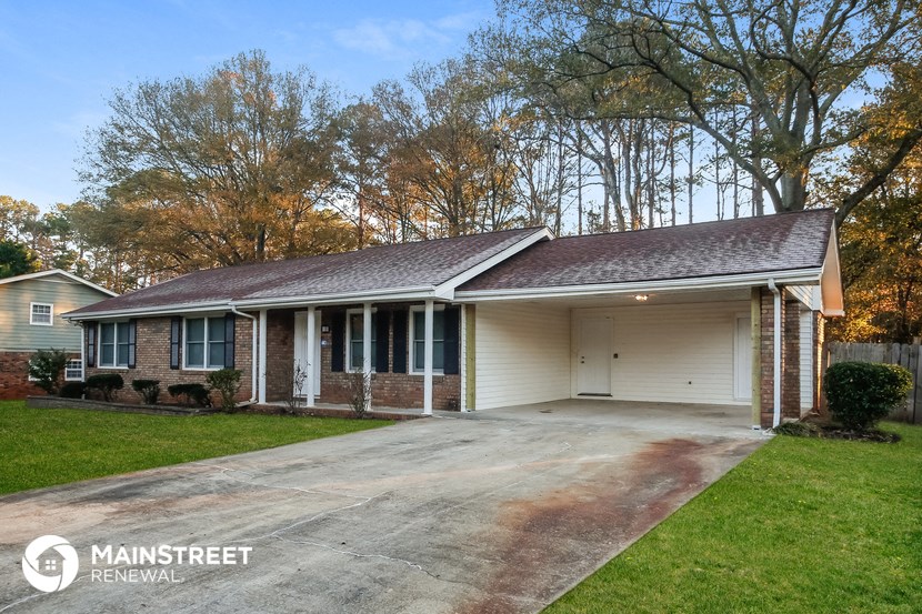 a white and brick house with a driveway and trees