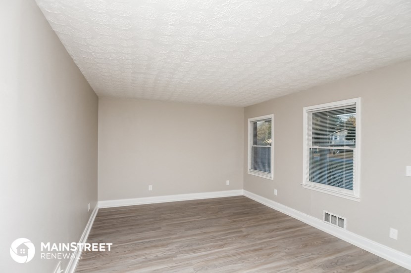 the spacious living room with a large window and wood flooring