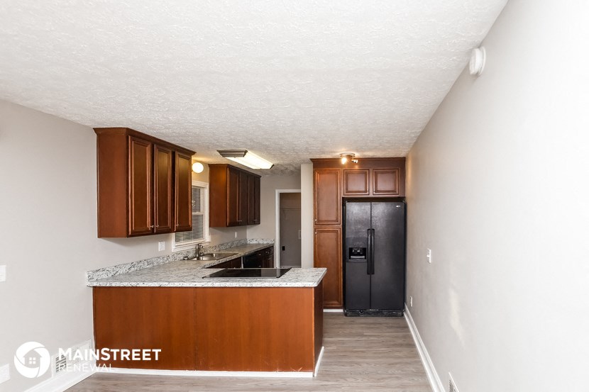 a kitchen with wood cabinets and granite counter tops and a black refrigerator