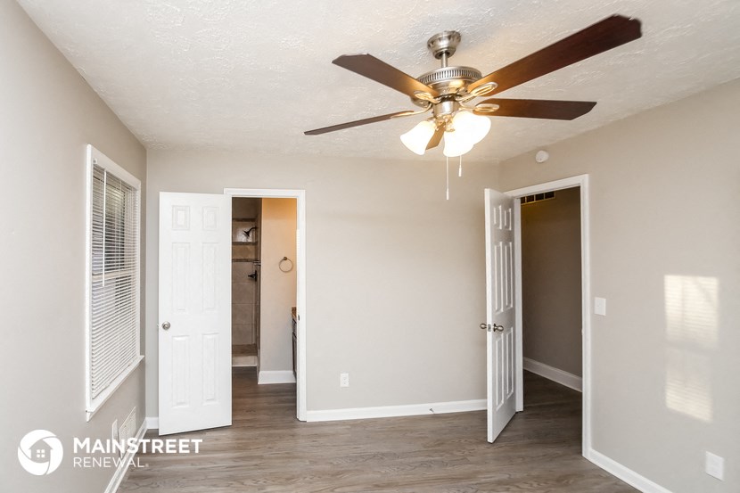 a living room with a ceiling fan and a door to a bathroom
