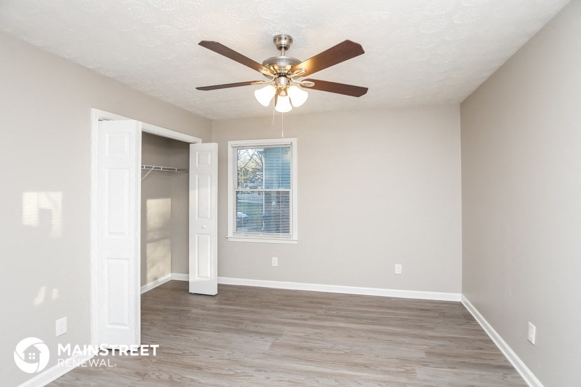 an empty room with a ceiling fan and a closet