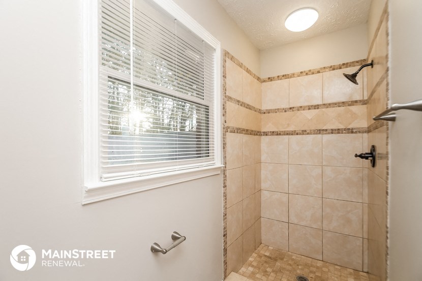 the master bathroom has a large shower and a large window