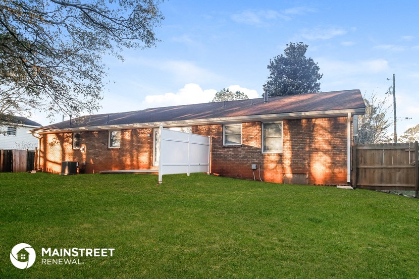 the front of a brick house with a yard and a white garage door
