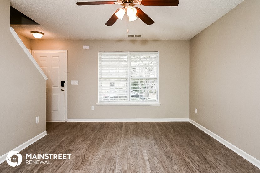 an empty living room with a ceiling fan and a window