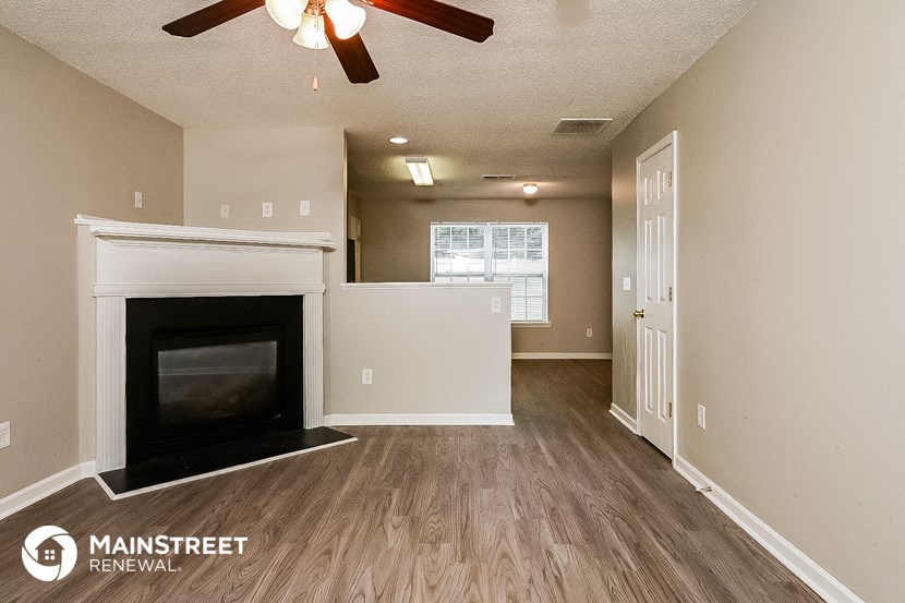 the living room and dining room of an apartment with a fireplace