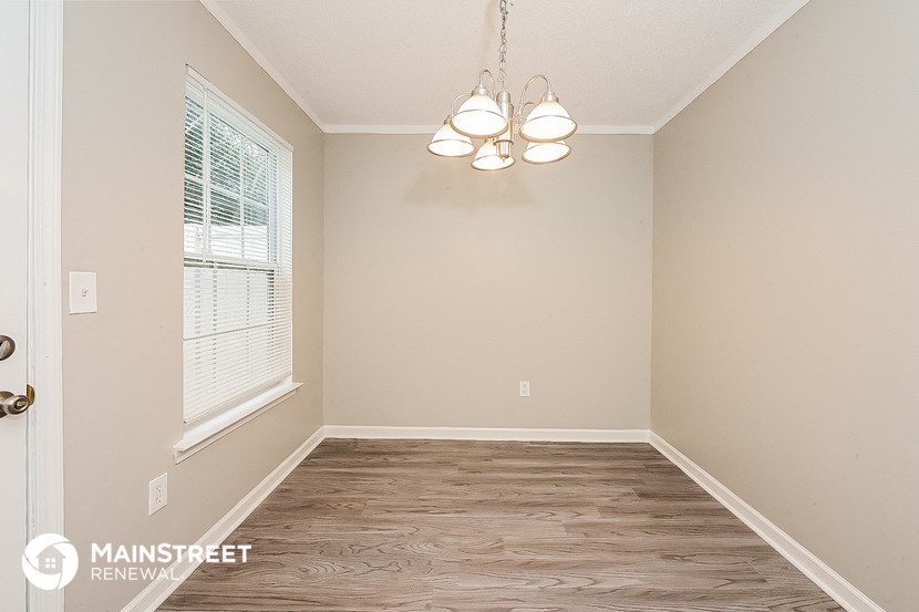 the living room of a home with wood flooring and a window