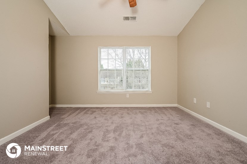 the spacious living room with carpeting and a window