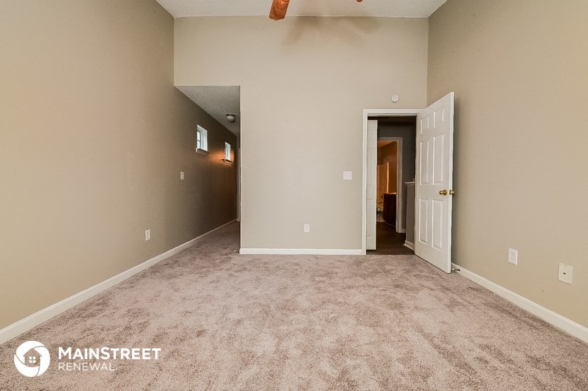 a empty living room with carpet and a door to a hallway