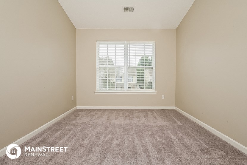 the spacious living room of an apartment with carpet and a window