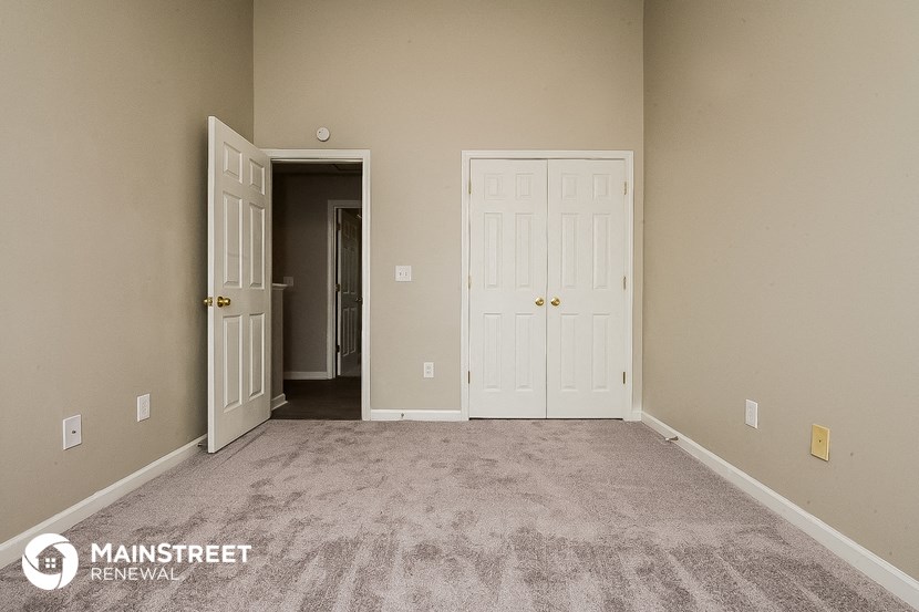 a carpeted room with two doors and a door to a closet