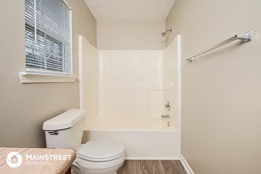 a bathroom with a toilet and a tub and a window