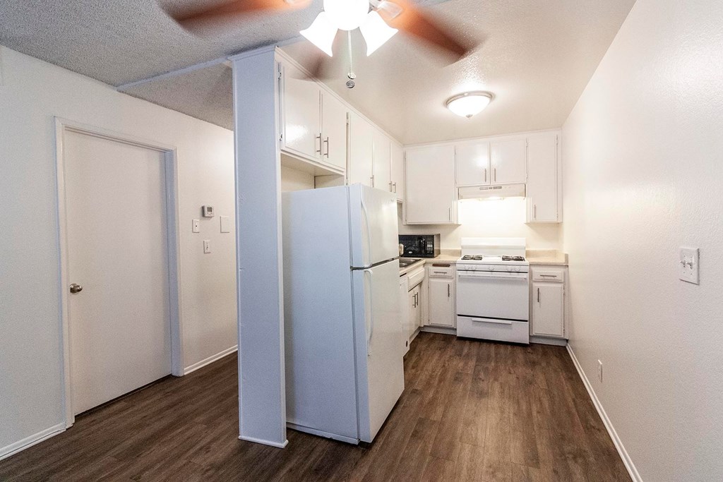 A kitchen with white appliances and cabinets.