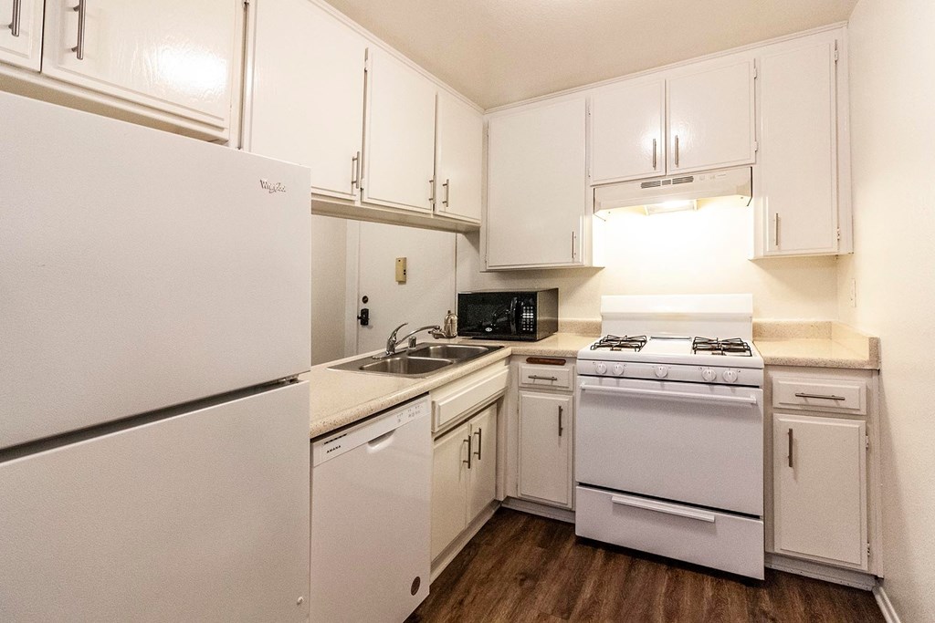 A white kitchen with a refrigerator, oven, and microwave.