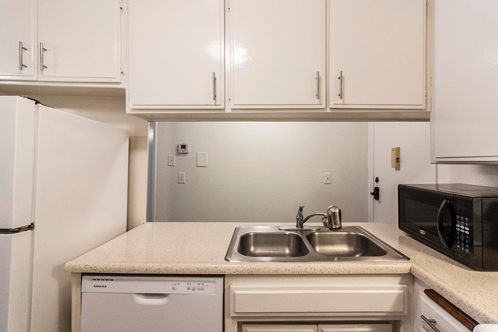 A kitchen with a white fridge, microwave, and dishwasher.