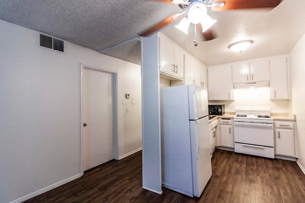 A kitchen with white appliances and cabinets.