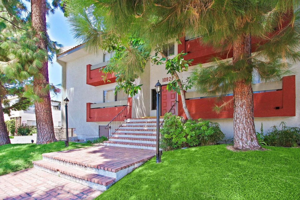 A house with a red awning and a tree in front.