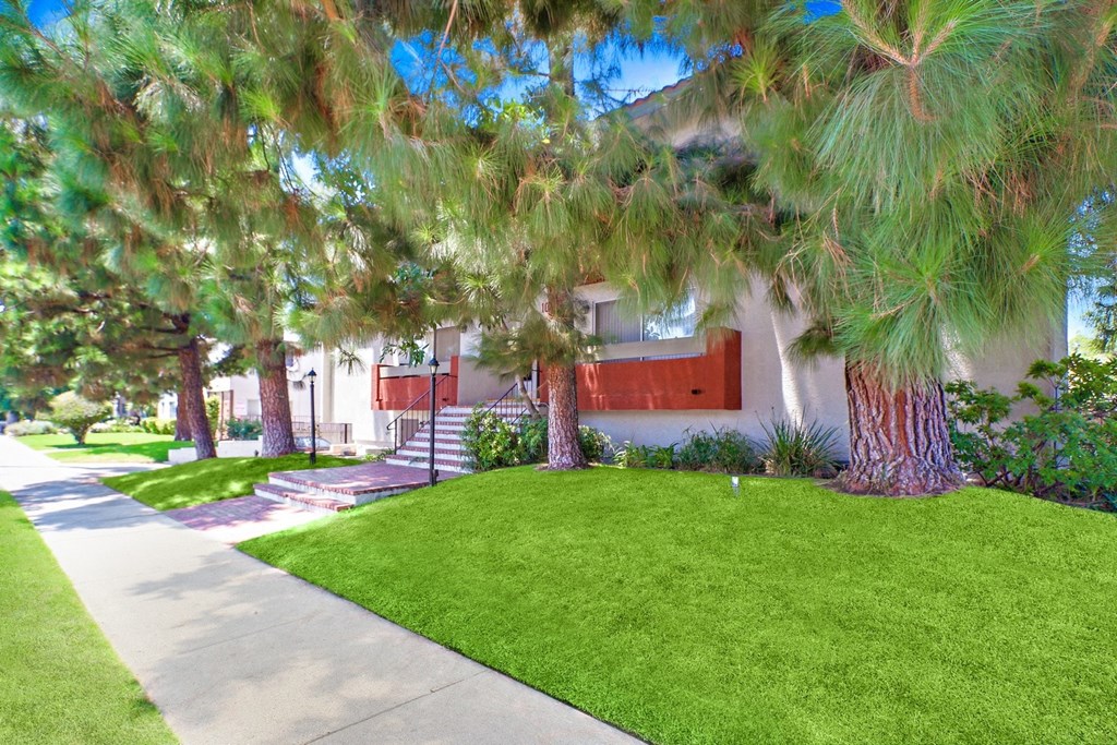 A house with a red door is surrounded by greenery.