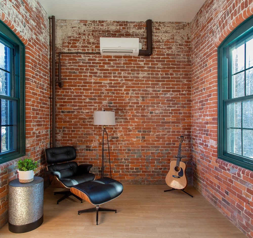 a living room with a brick wall and a chair and a guitar