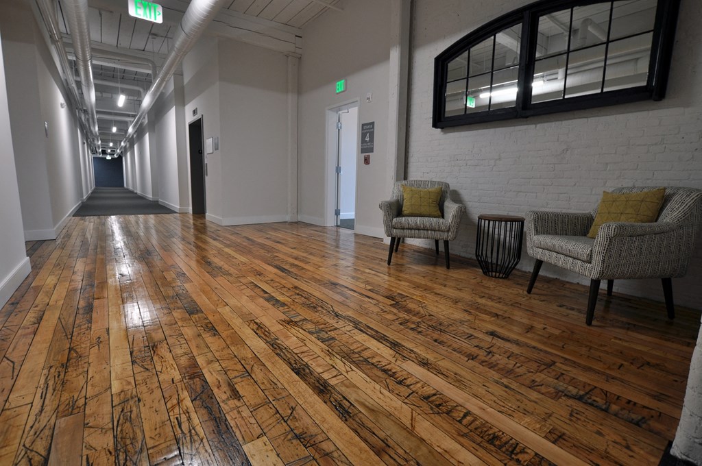 a hallway with chairs and a wooden floor in a building