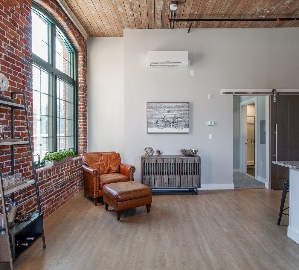 a living room with a leather chair and a radiator and a brick wall