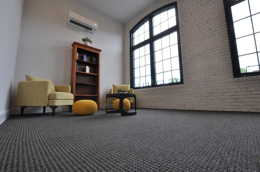 a living room with chairs and a table and a brick wall