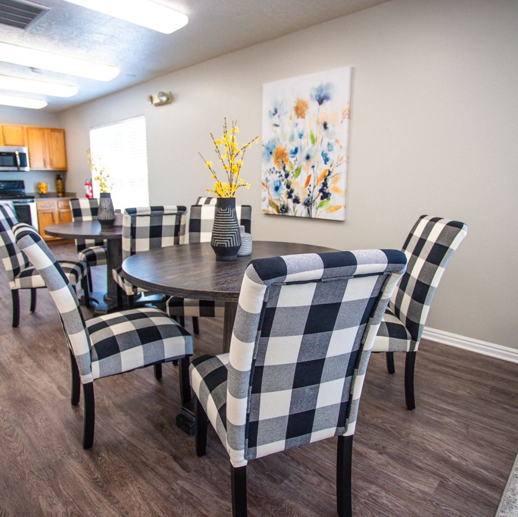 A dining room with a checkered tablecloth and chairs.