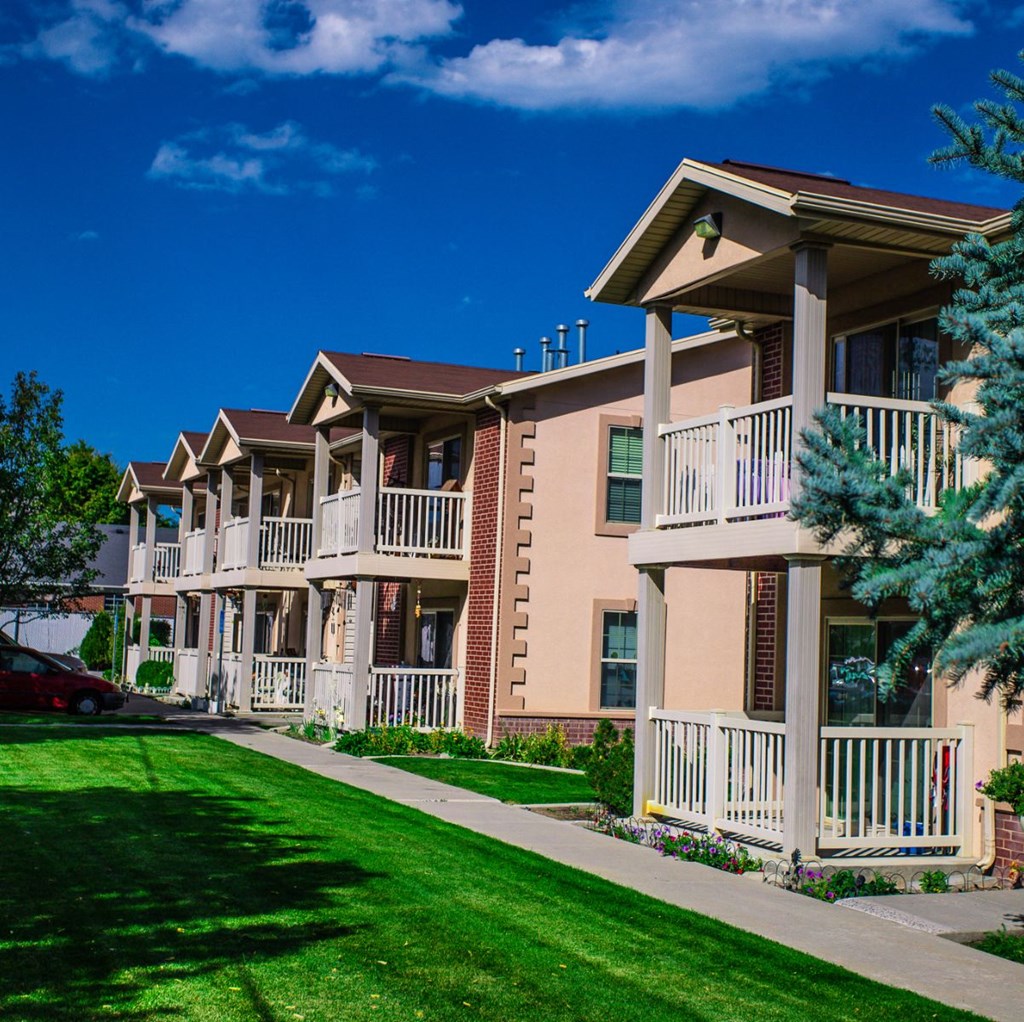 A row of apartment buildings with green lawns in front.