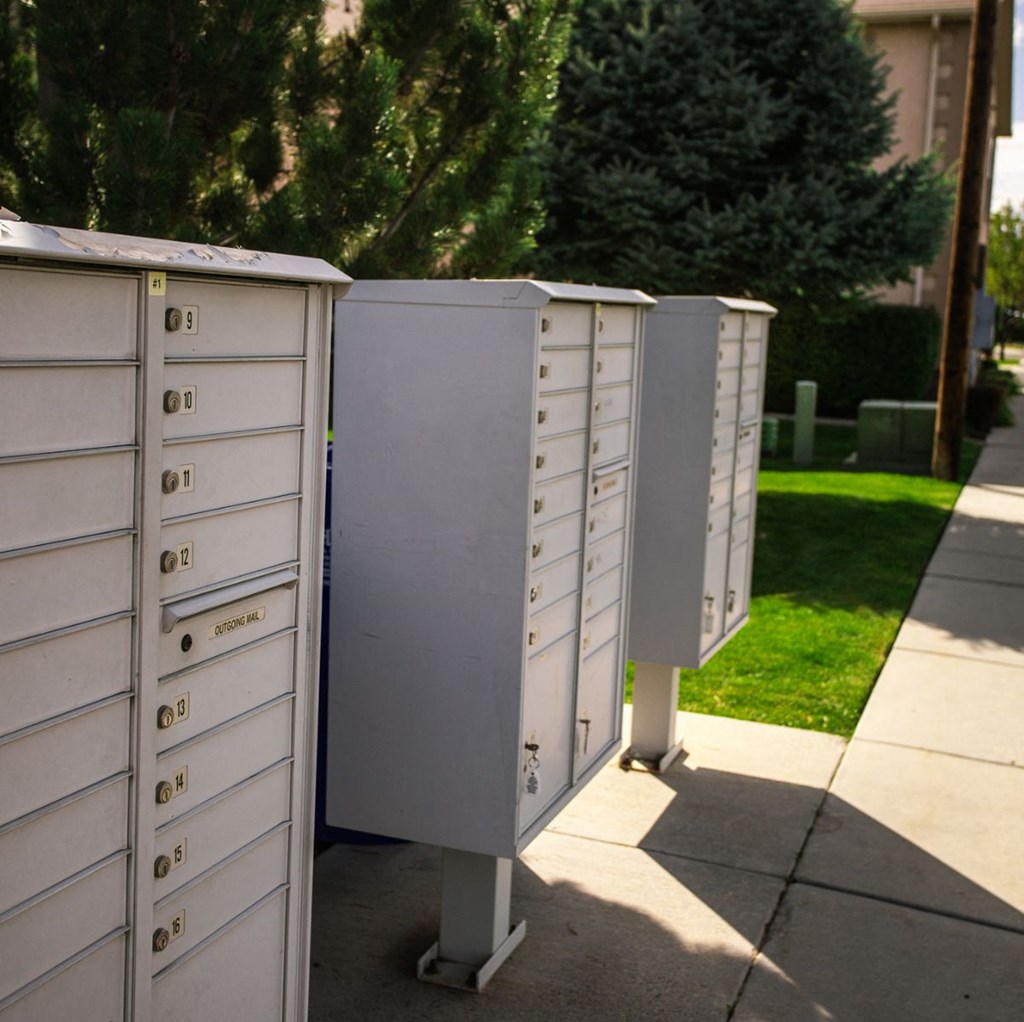 A row of white mailboxes are lined up on a sidewalk.