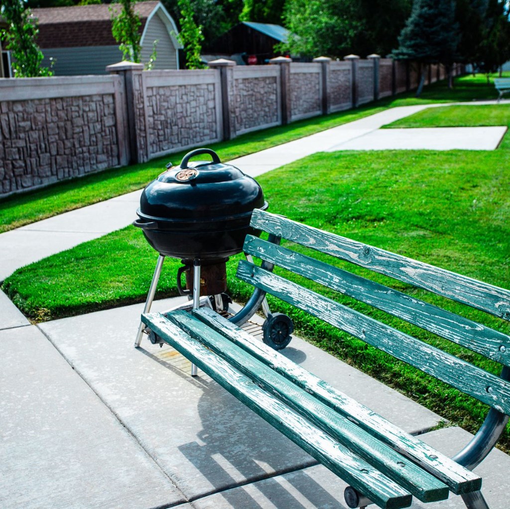 A green bench with a black grill next to it.