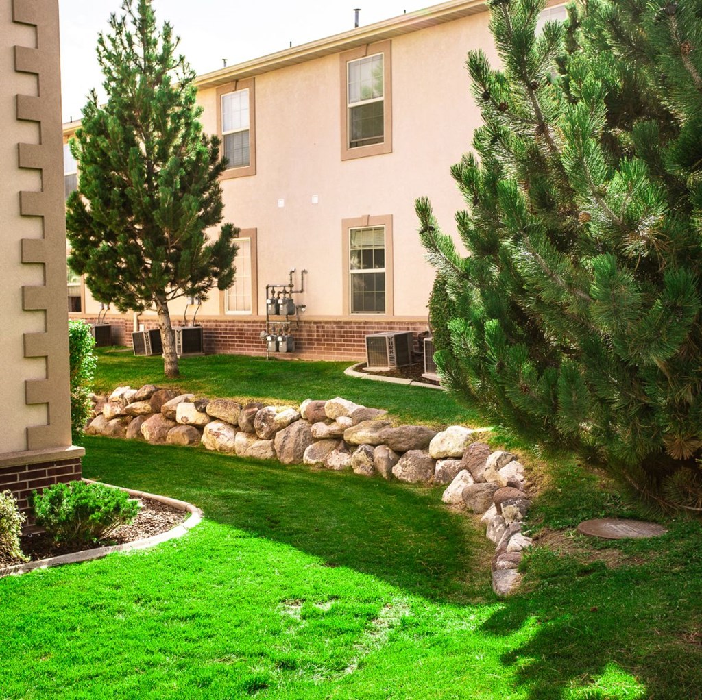 A house with a green lawn and a stone wall.
