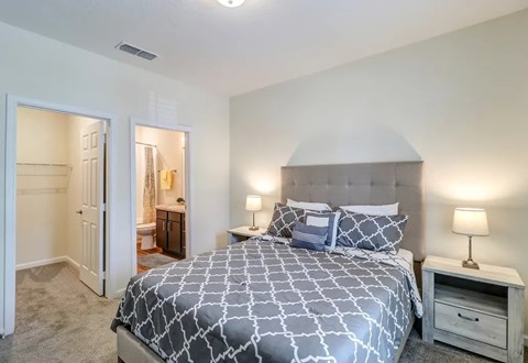A bedroom with a large bed and a nightstand with a lamp.