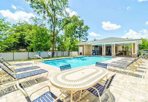 A pool surrounded by lounge chairs and a building in the background.