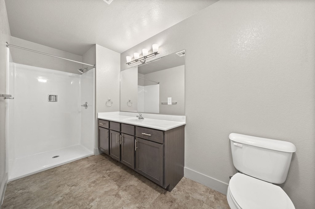 a bathroom with a toilet sink and mirror and a shower