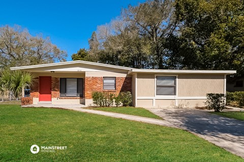 a small bungalow with a red door and a lawn