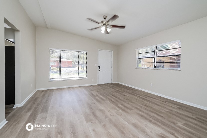 an empty living room with wood flooring and a ceiling fan