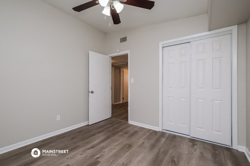 the spacious living room of an apartment with a ceiling fan