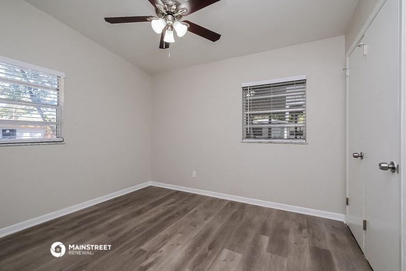 the spacious living room has a ceiling fan and wood flooring