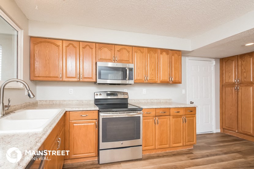 a kitchen with wooden cabinets and a stove and microwave