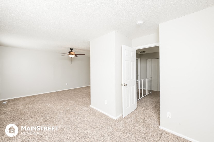 a bedroom with white walls and a ceiling fan