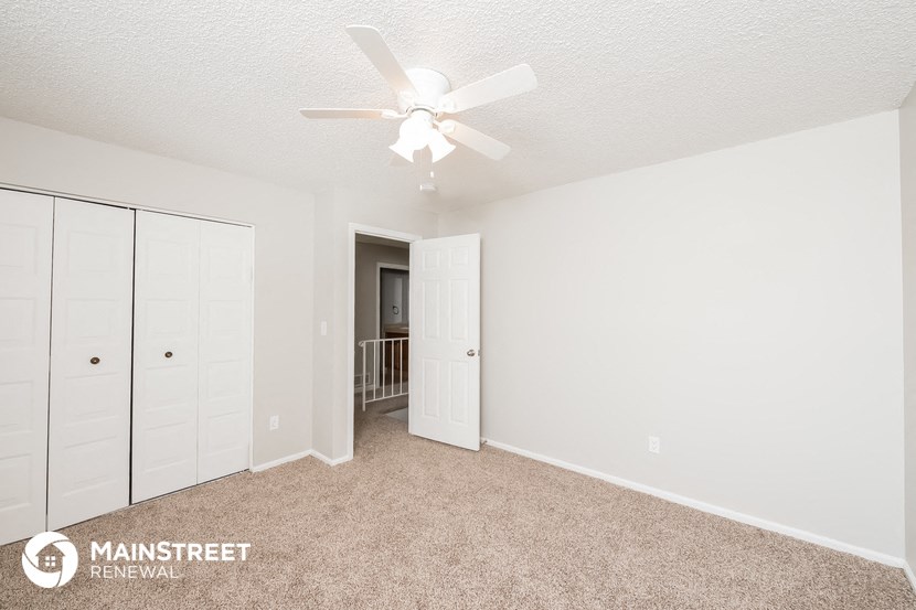 the spacious living room with closet and ceiling fan