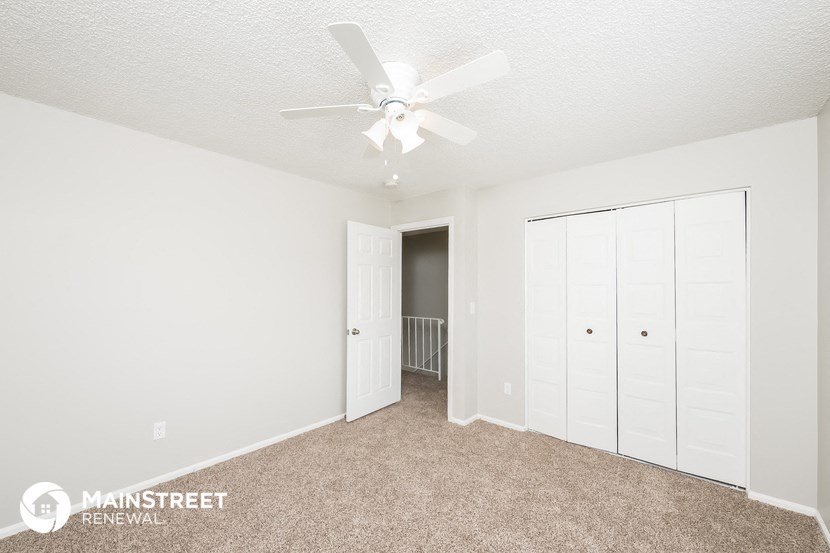 a bedroom with a ceiling fan and a closet