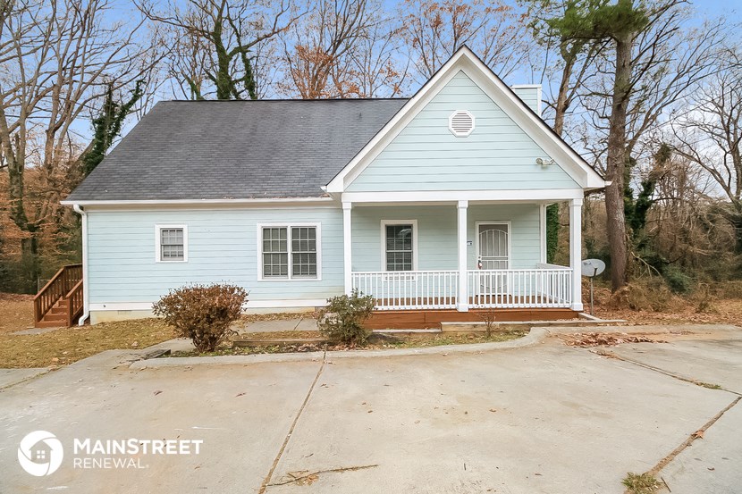 a small blue house with a porch and a driveway
