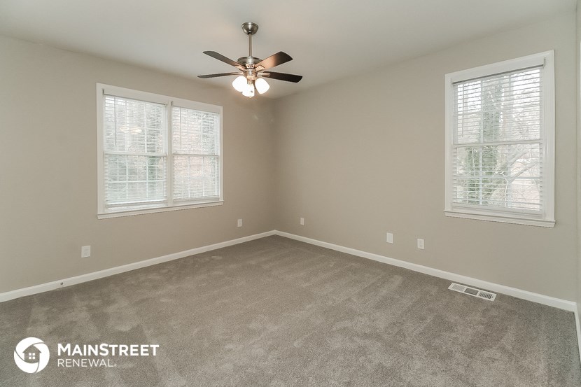 the spacious living room with carpeting and a ceiling fan