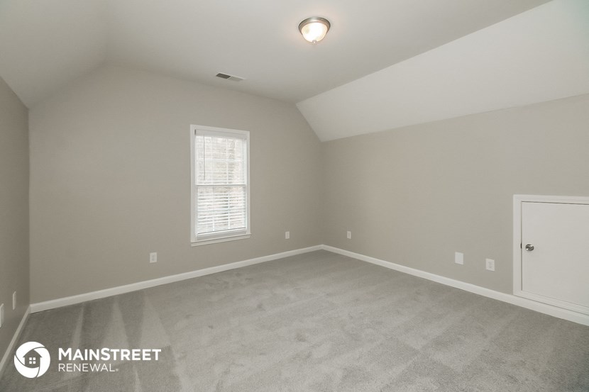 the spacious living room with carpeting and a window