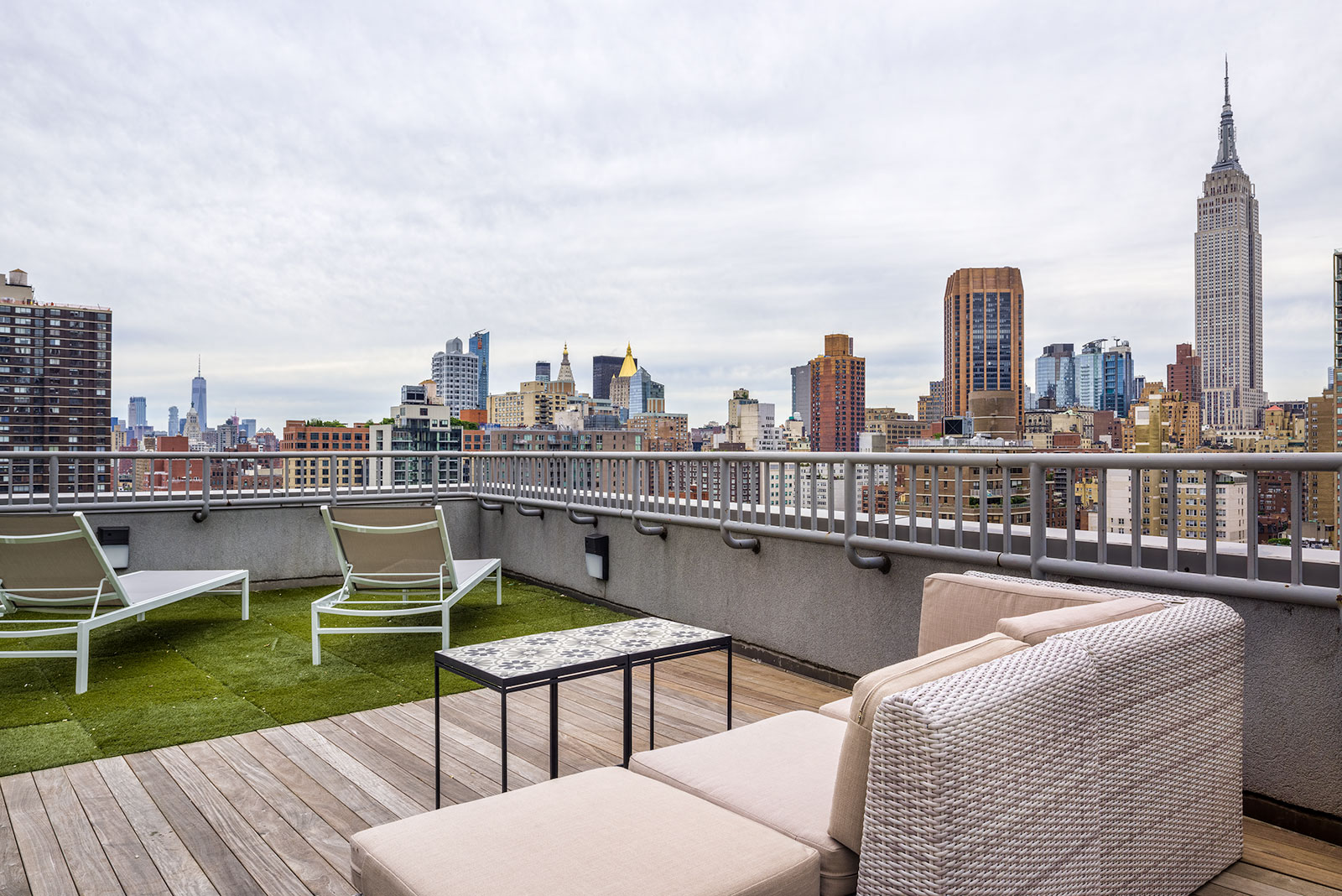 a view of the empire state building from a rooftop terrace with furniture and chairs