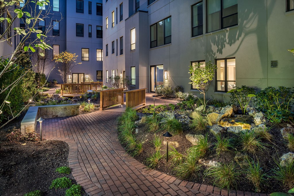 a courtyard with benches and plants in front of a building