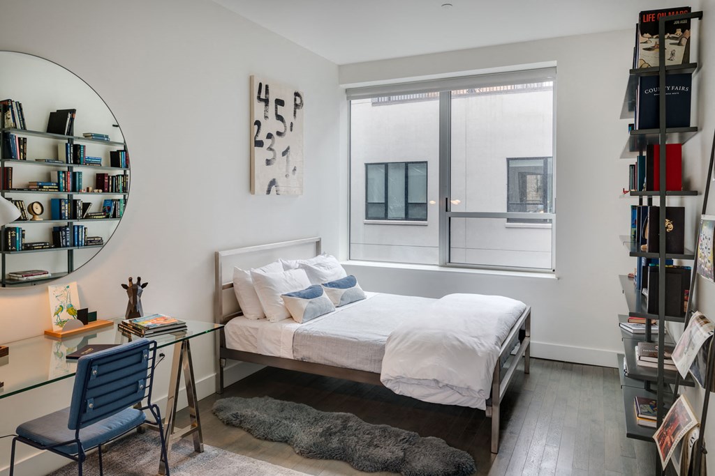 a bedroom with a bed and a desk and a window