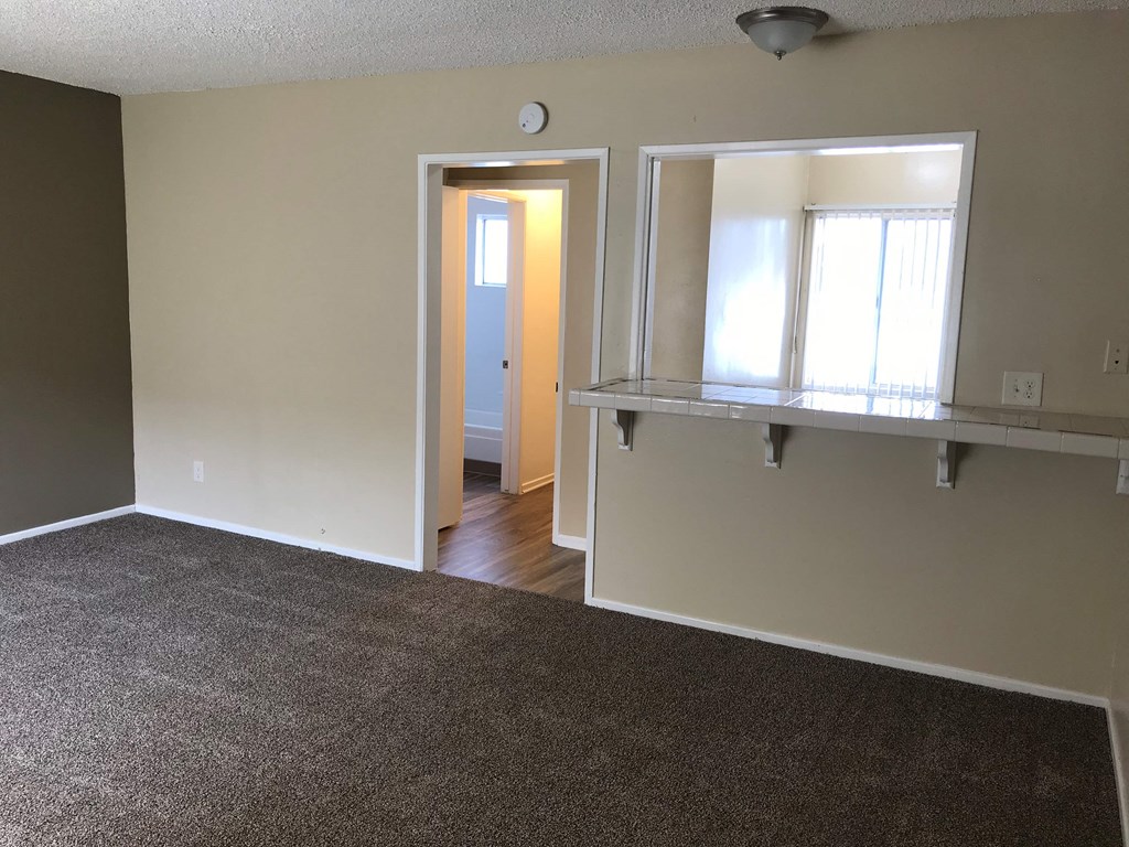an empty living room with a large window and a counter