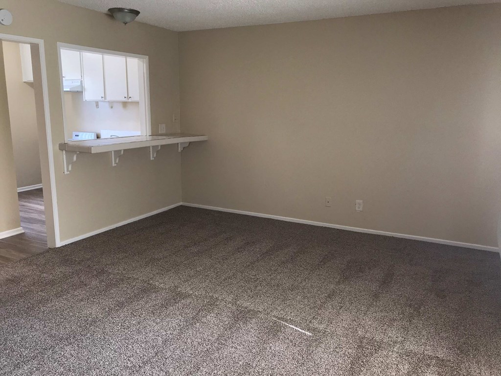 a empty living room with a carpeted floor and a desk